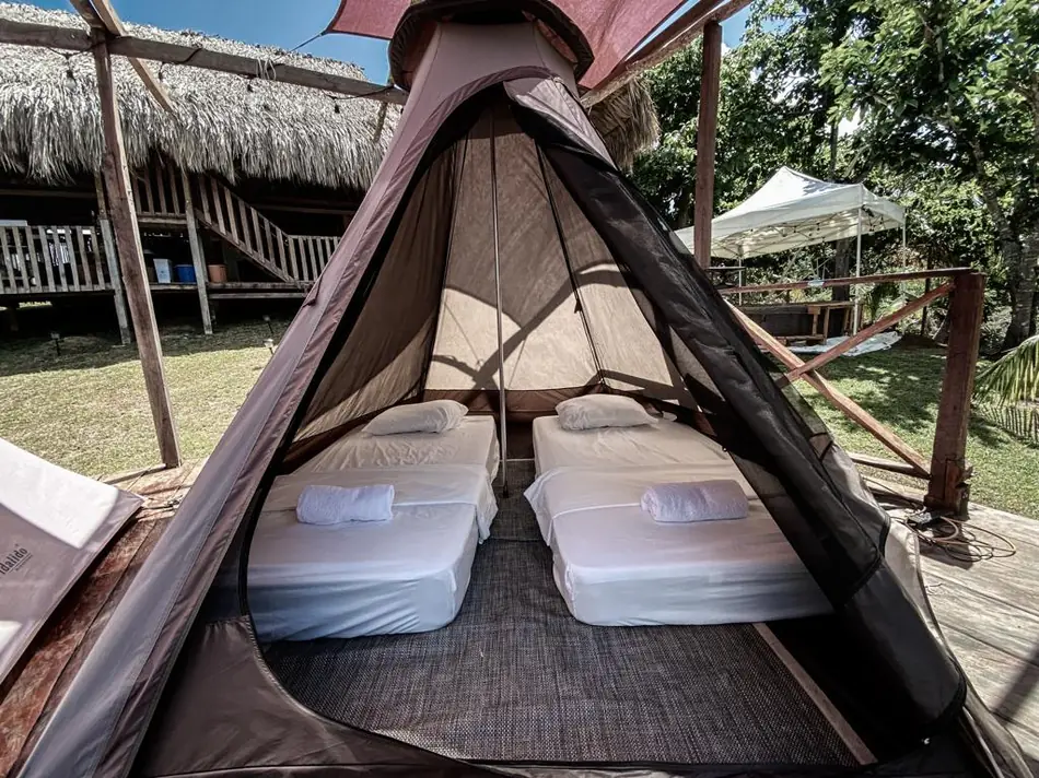 Interior de un tipi con dos colchones tendidos y mosquitero
