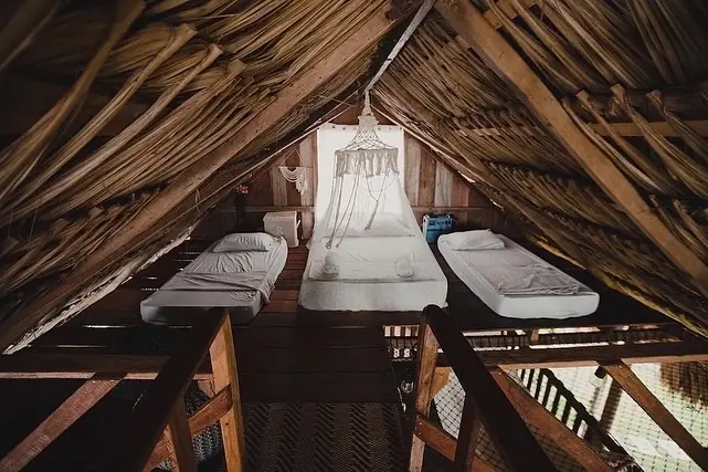 Altillo de dos pisos con cama queen y colchones twin bajo el techo de penca