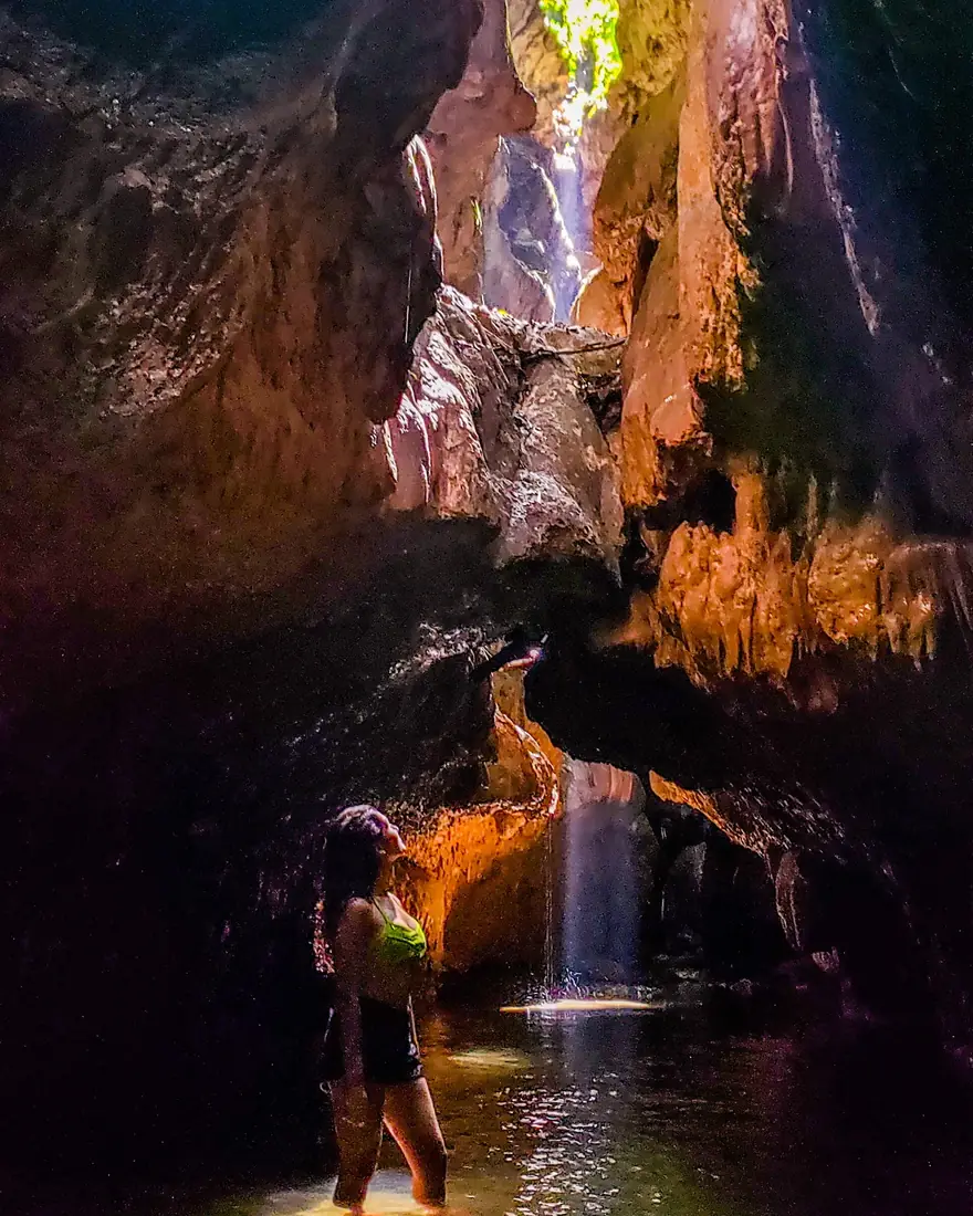 Una cascada de luz y agua dentro de la cueva, con un visitante abajo