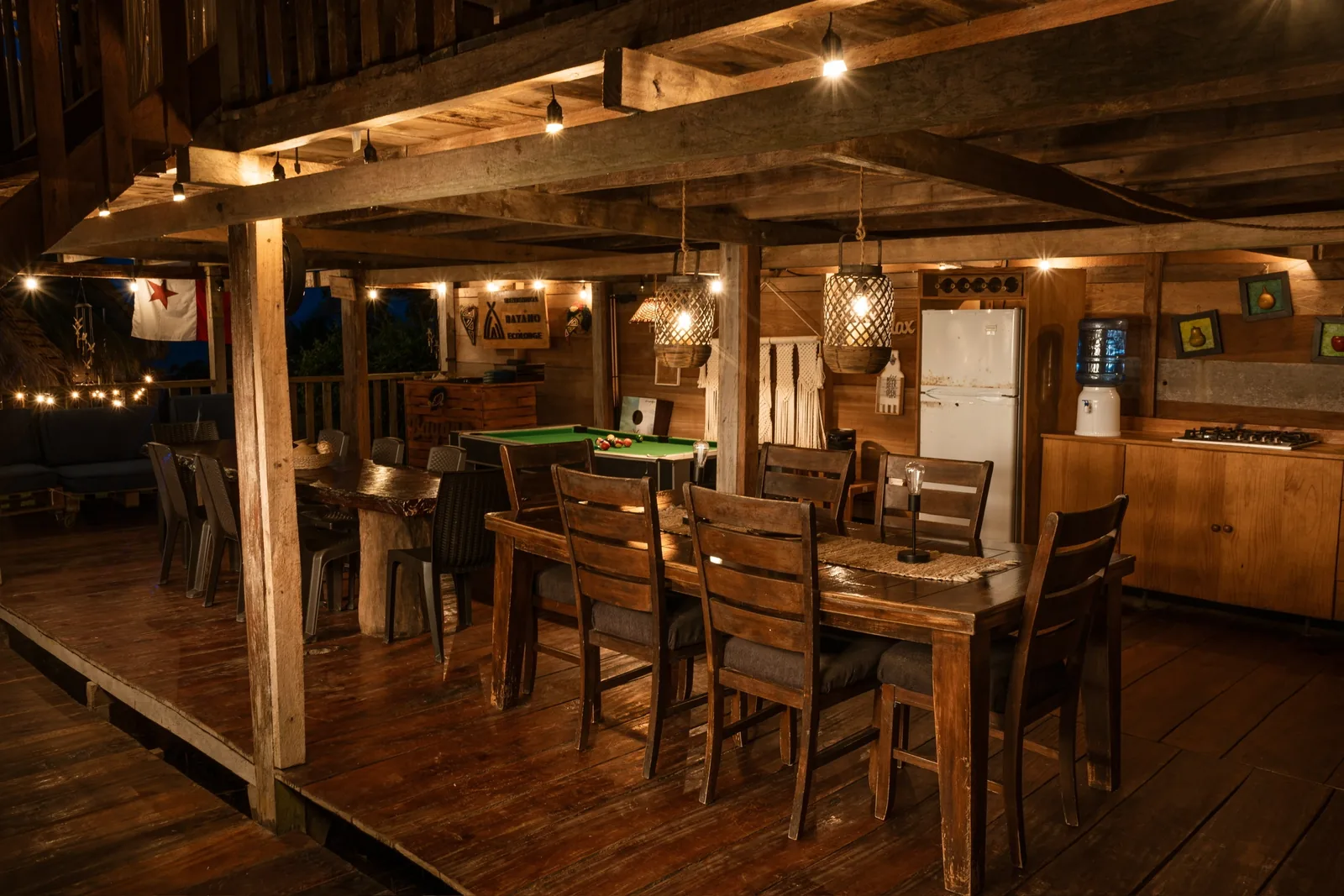 El lobby del ecolodge al anochecer: mesas de madera, luces colgantes y el letrero de Bayano Ecolodge