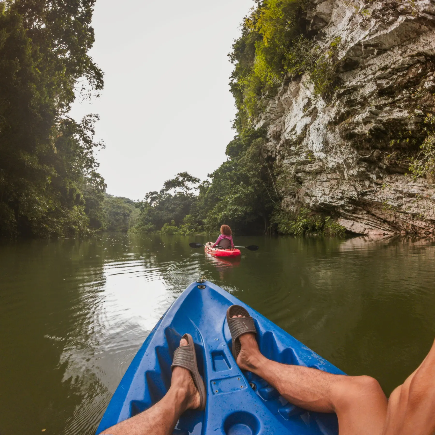 First-person view from a blue kayak between the canyon walls